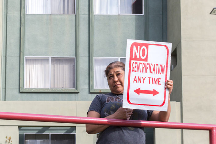 Tenant holding sign modeled after a "no parking" sign that says "No gentrification any time."