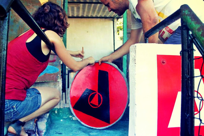 Two cuban anarchists prepare a sign with logo of Abra social center to be hung