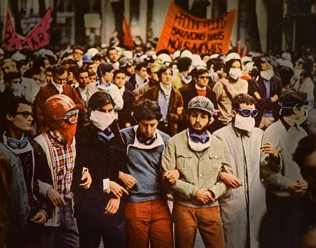 Young demonstrators, arms linked and banners in the background, march during the France 1968 rebellion. 