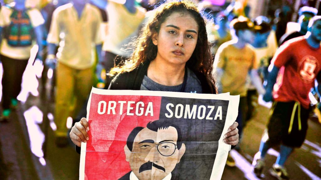 Woman carrying sign comparing former Nicaraguan dictator Somoza with current President Daniel Ortega