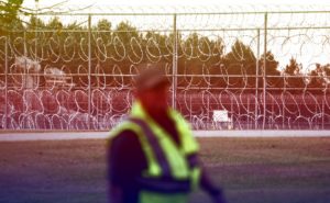 Image of guard in front of prison barbed wire