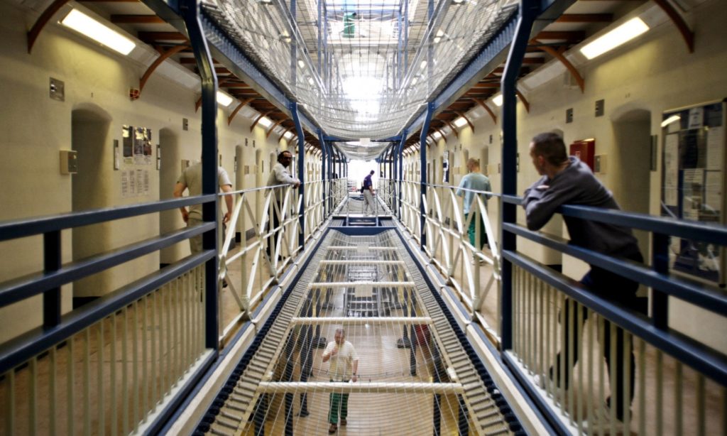 Photo inside multi-story prison. A prisoner leans on the railing.