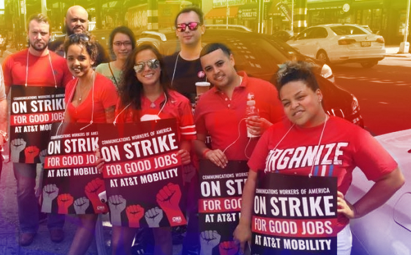 Group of striking AT&T workers posing together with red shirts and strike signs.