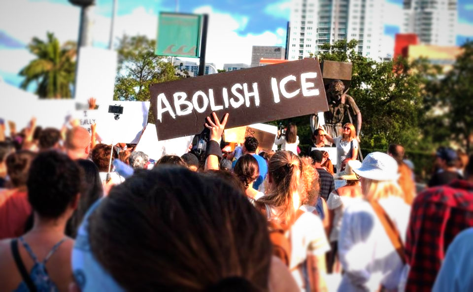 Crowd marching in protest of detention of migrants and children in Miami. Handmade sign in center says "Abolish ICE"