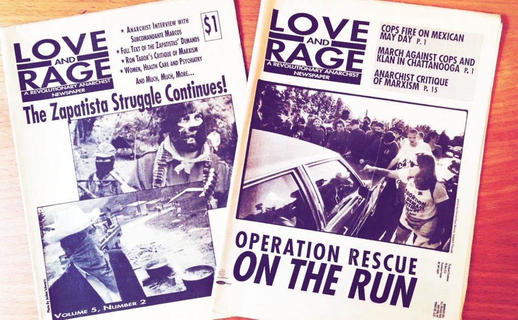 Photo of two editions of Love and Rage newspaper. The cover for one discusses the Zapatista movement, the other abortion clinic defense.