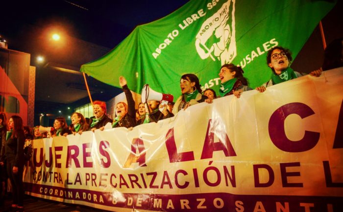 Women holding a banner leading a abortion rights protest in Chile.