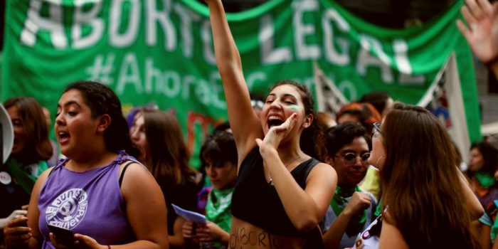 March for abortion rights in Chile. Women in fore ground, green banner in background.