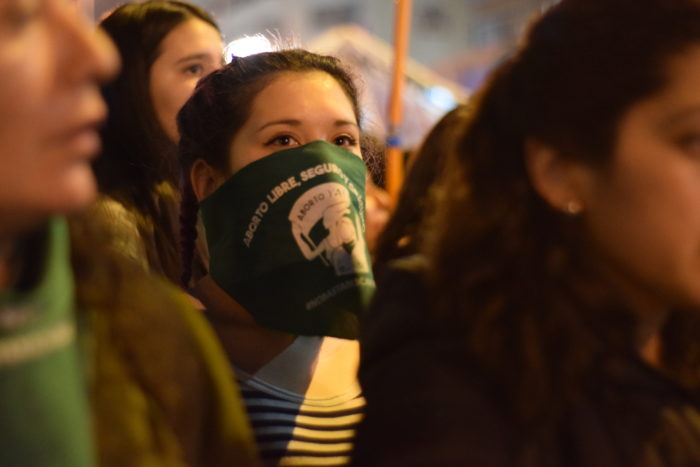 Feminist march, women in center frame wearing green bandanna. 