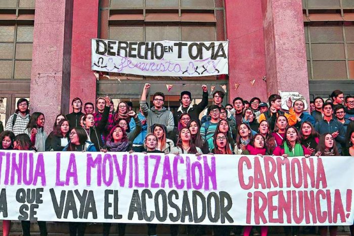 Students in front of a banner on the steps of the entrance to the University of Chile Law School entrance that they are occupying.